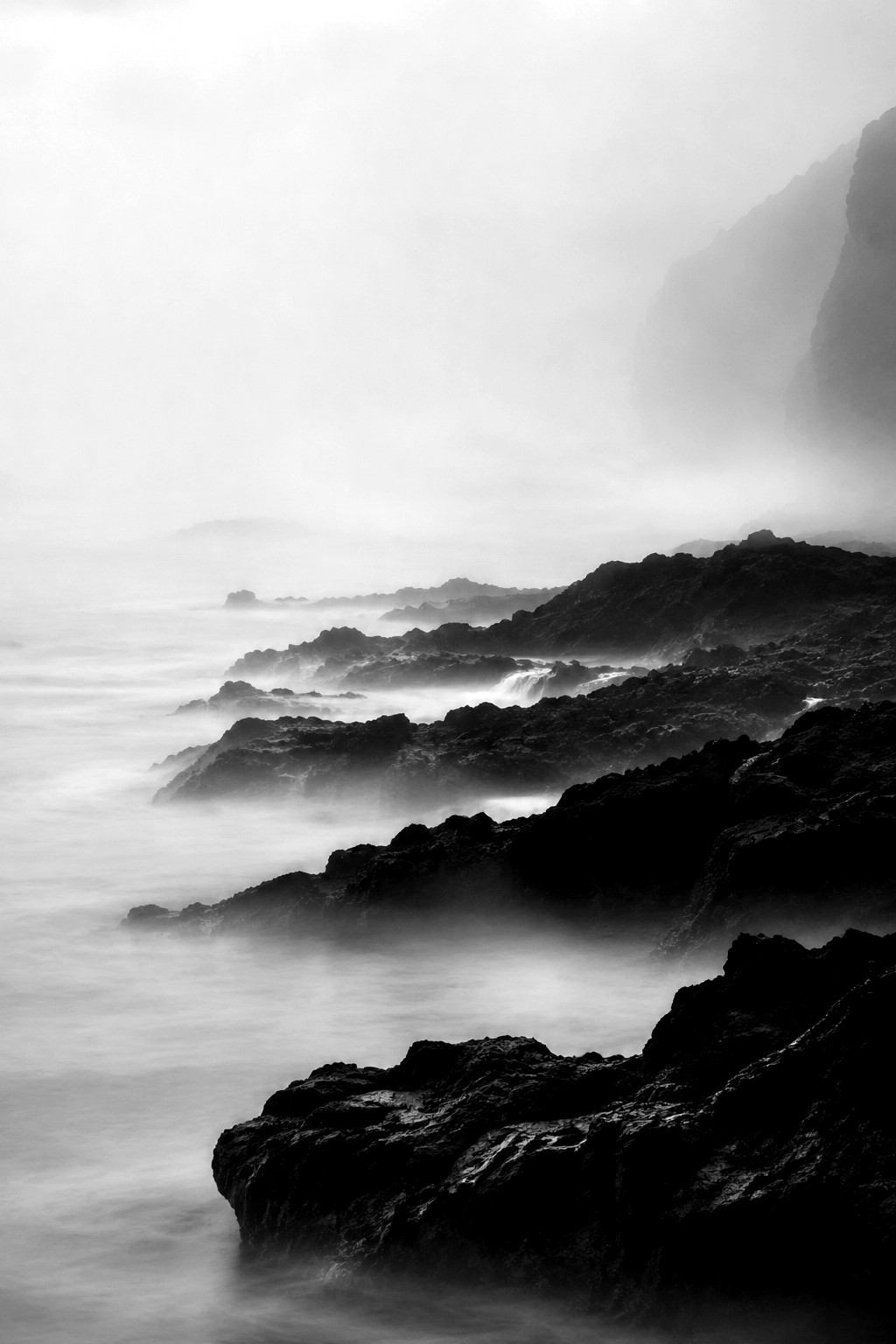 AI generated monochrome fine-art landscape of basalt shoreline and sea fog.